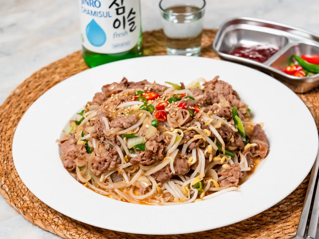 Thinly sliced beef brisket being stir fried in a hot wok with cooking oil