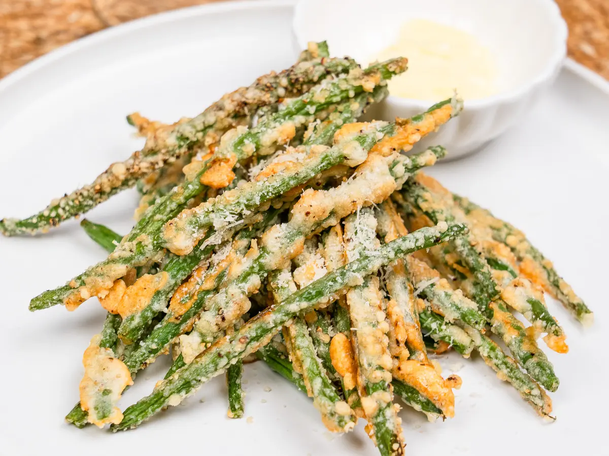air fryer green beans coated in parmesan on a white plate