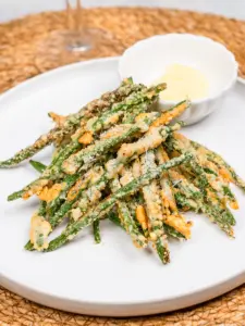 air fryer green beans coated in parmesan on a white plate