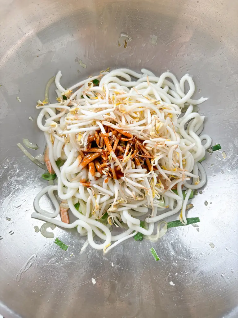 Tossing udon noodles on high heat with Korean sauce — final step of seafood udon stir fry
