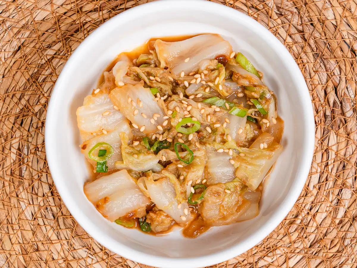Best Korean Cabbage Side Dish Recipe – Doenjang Baechu Namul authentic korean cabbage side dish baechu namul in white ceramic bowl with sesame seeds and green onion garnish