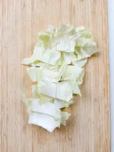 napa cabbage cut into 2cm pieces on wooden cutting board for korean cabbage side dish