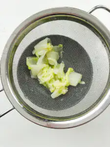 squeezing blanched napa cabbage with both hands to remove water for korean cabbage banchan recipe