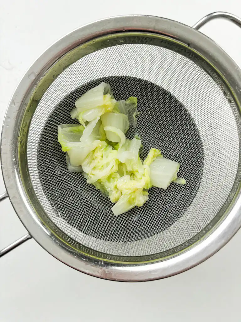 Best Korean Cabbage Side Dish Recipe – Doenjang Baechu Namul squeezing blanched napa cabbage with both hands to remove water for korean cabbage banchan recipe