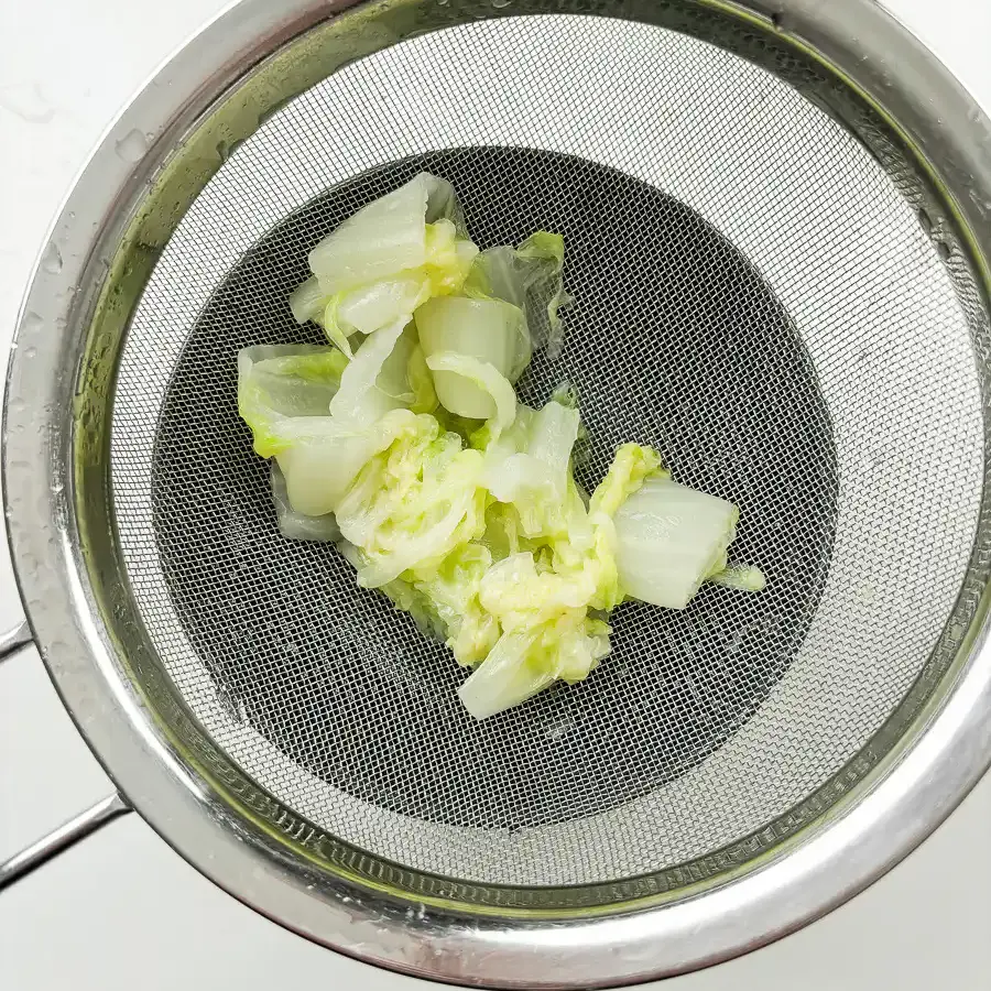 Best Korean Cabbage Side Dish Recipe – Doenjang Baechu Namul squeezing blanched napa cabbage with both hands to remove water for korean cabbage banchan recipe