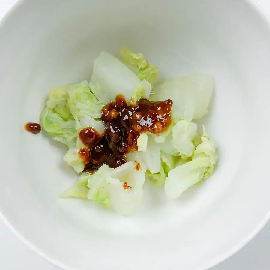 Best Korean Cabbage Side Dish Recipe – Doenjang Baechu Namul adding doenjang sauce to blanched cabbage by hand in a mixing bowl for authentic korean cabbage side dish
