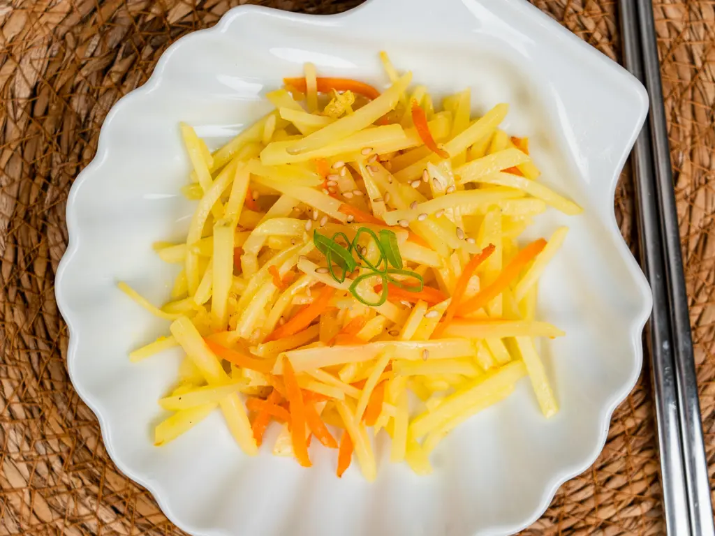 Restaurant-style Korean potato side dish gamja bokkeum plated with chopsticks on the side