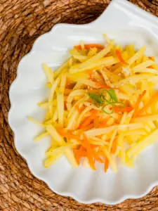 Restaurant-style Korean potato side dish gamja bokkeum plated with chopsticks on the side