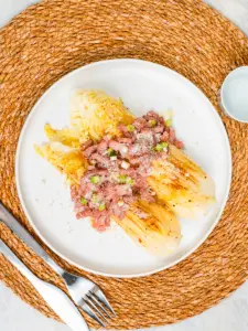 pan fried cabbage steaks with bacon and parmesan on a white ceramic plate