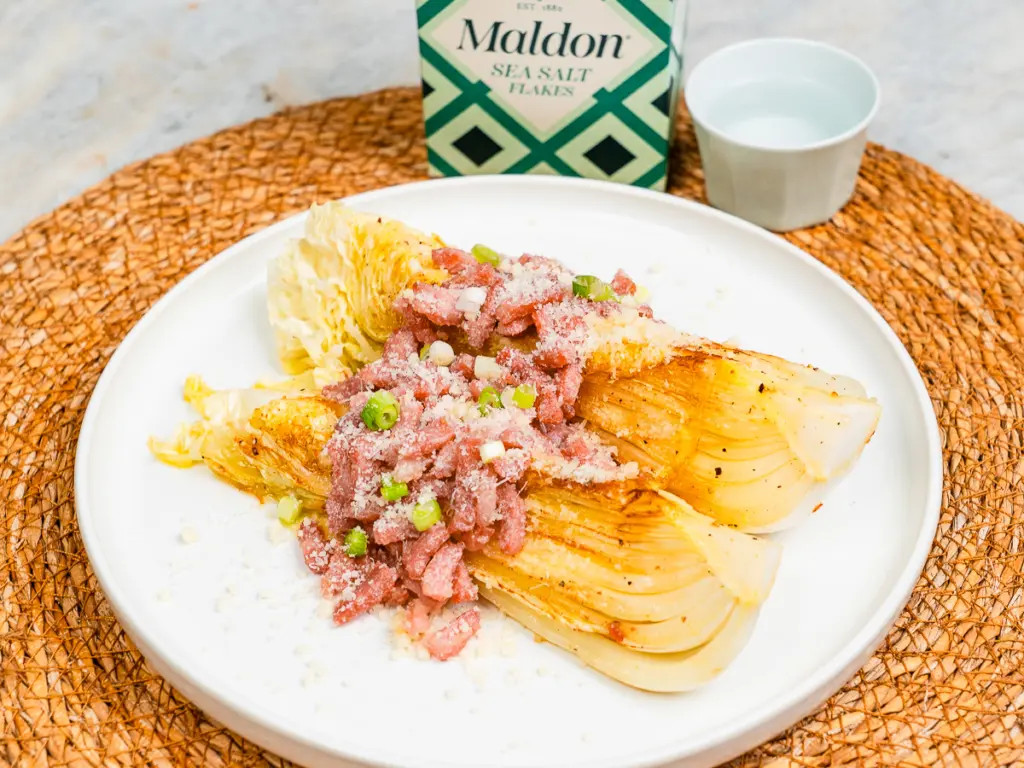 finished pan fried cabbage steaks with cheese being served from pan to plate