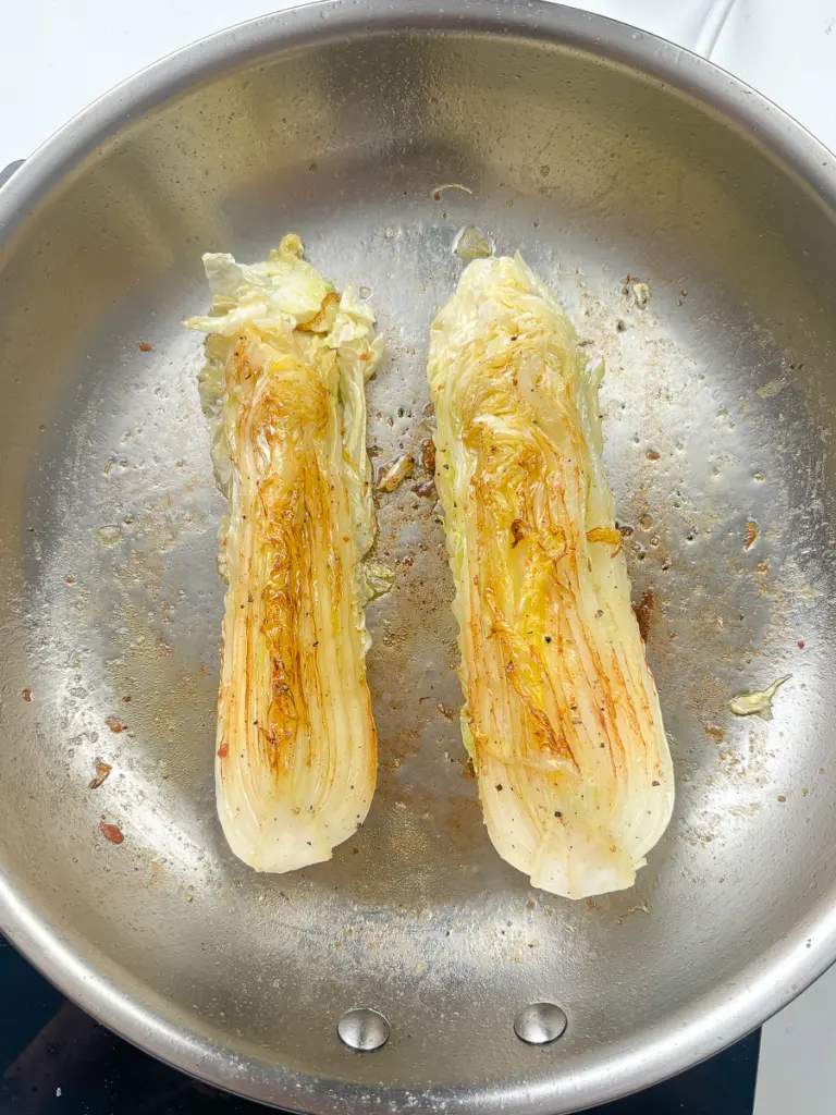 pan fried cabbage steaks searing in cast iron skillet with golden brown char