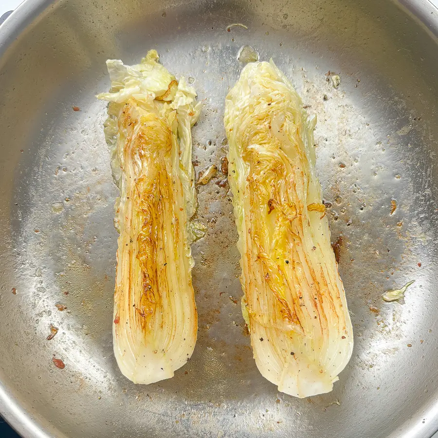 pan fried cabbage steaks searing in cast iron skillet with golden brown char