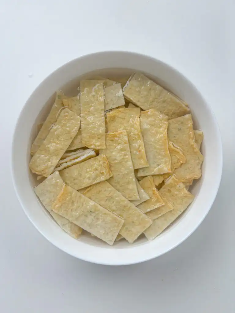 Sliced Korean fish cake strips soaking in hot water to remove excess oil