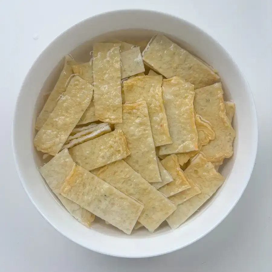 Sliced Korean fish cake strips soaking in hot water to remove excess oil