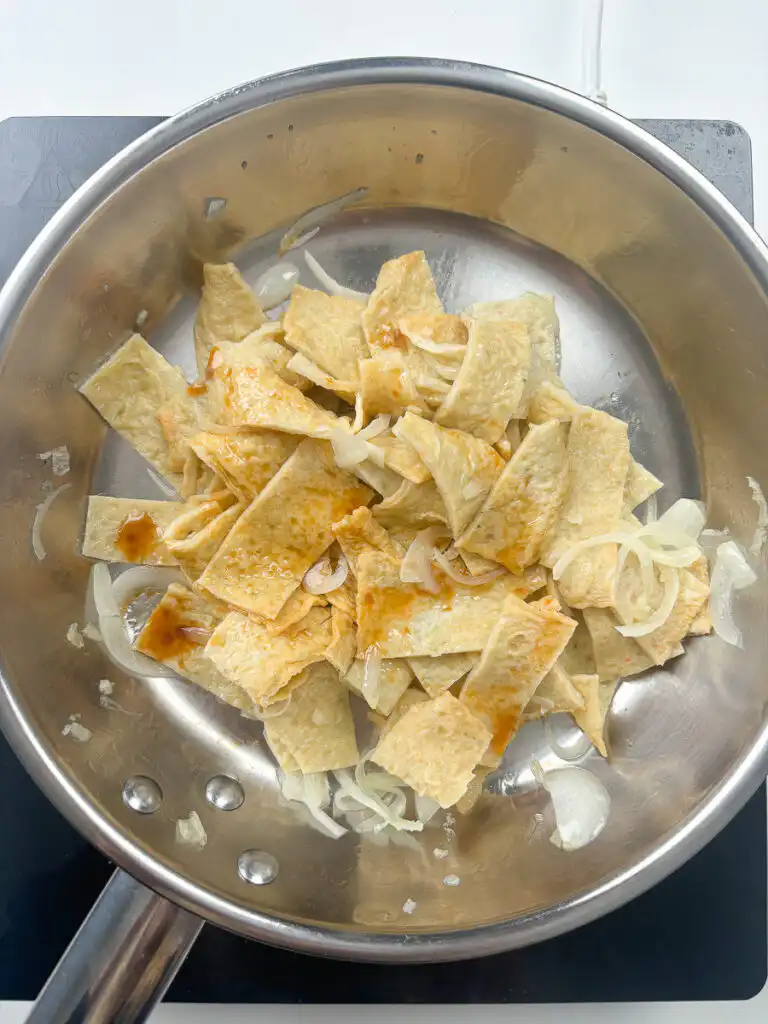 Pouring sweet soy sauce over stir fried fish cake in a hot pan