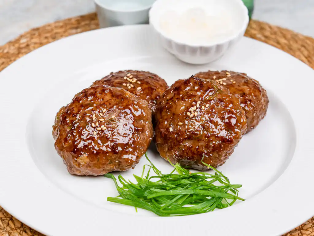 Pan-fried tteokgalbi topped with chopped scallions and sesame seeds
