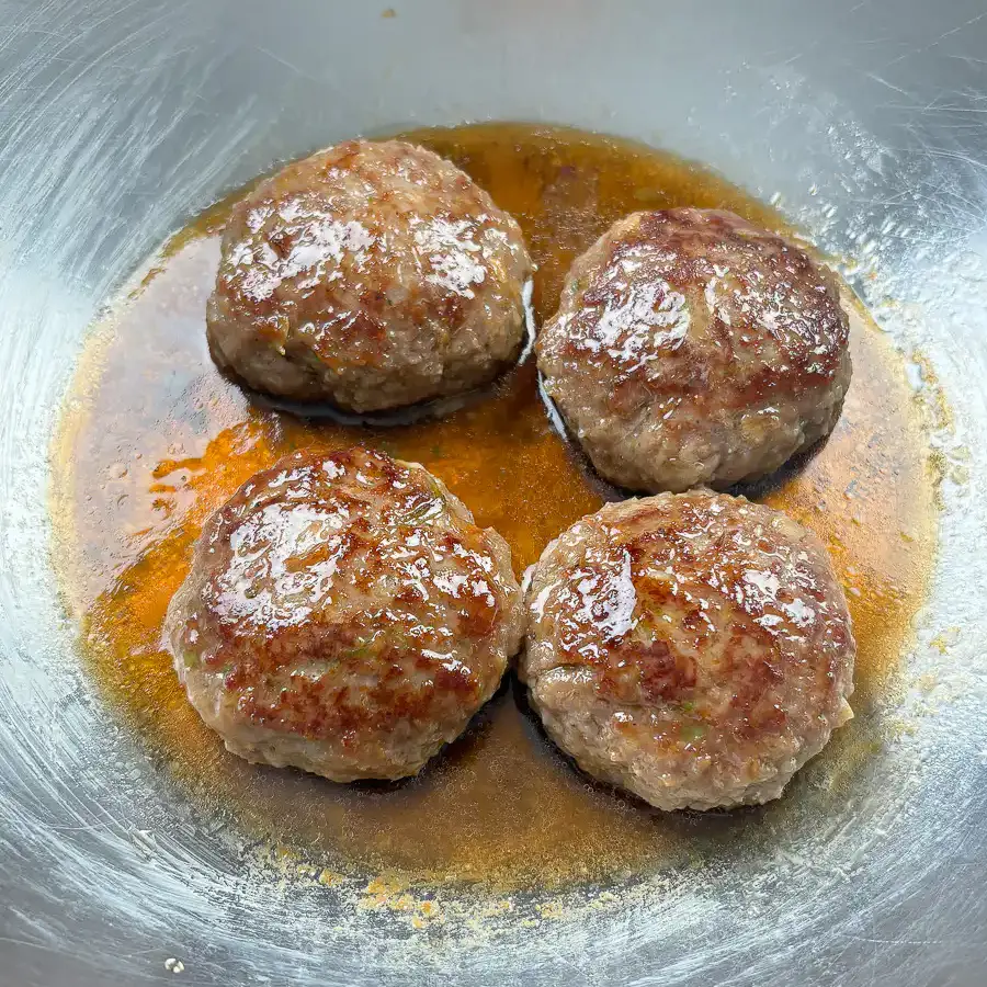 Sweet soy glaze being poured over pan-fried tteokgalbi