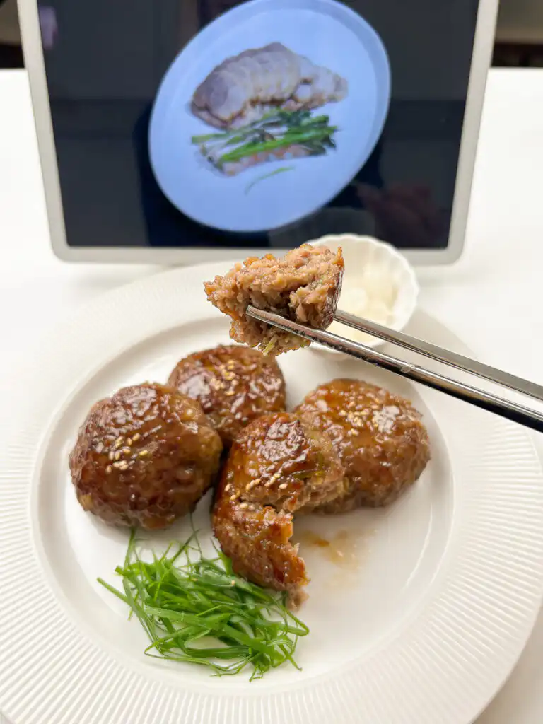 Bite of tteokgalbi lifted with chopsticks revealing tender texture