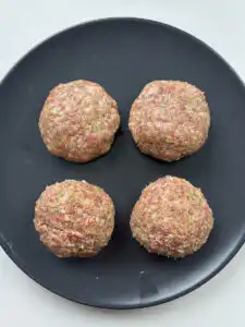 Hands slapping and kneading tteokgalbi patties to build texture