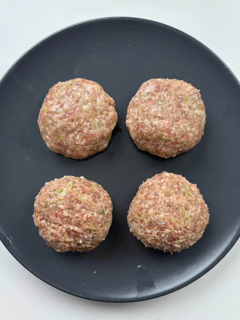 Hands slapping and kneading tteokgalbi patties to build texture