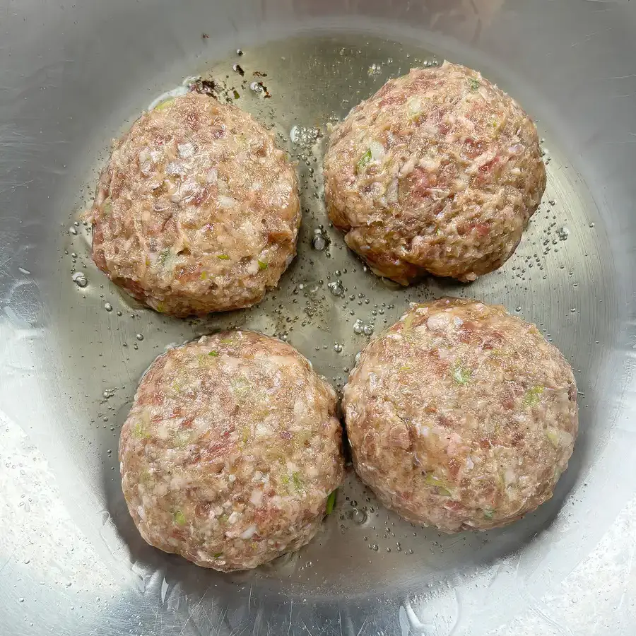 Four shaped tteokgalbi patties arranged before pan-frying