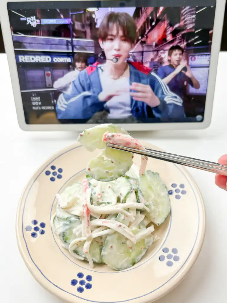 Lifting cucumber crab salad from ceramic serving bowl