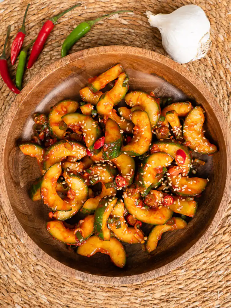 Overhead shot of cubed cucumber kimchi with sesame seeds on linen background