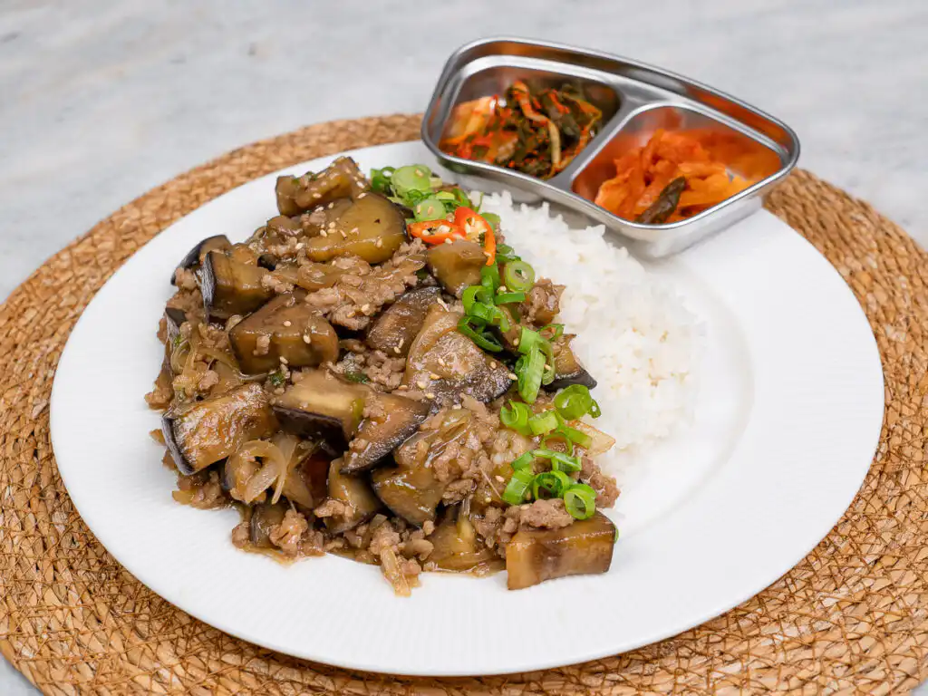 Korean eggplant rice bowl next to small side dishes on a table