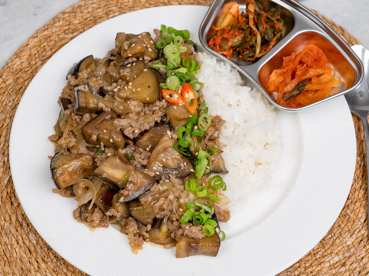Korean eggplant rice bowl next to small side dishes on a table