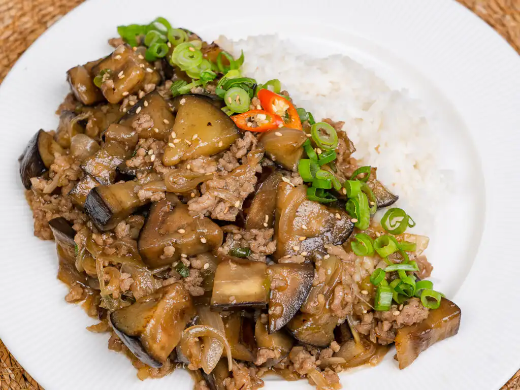 Eggplant oyster sauce recipe in a bowl with steam rising from hot rice