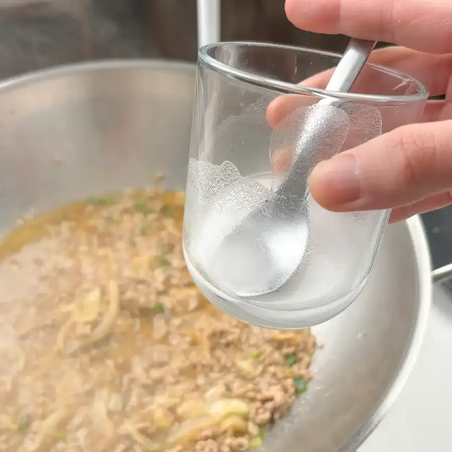 Potato starch slurry being added gradually to thicken the sauce