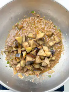 Seared eggplant added back into glossy oyster sauce in a pan