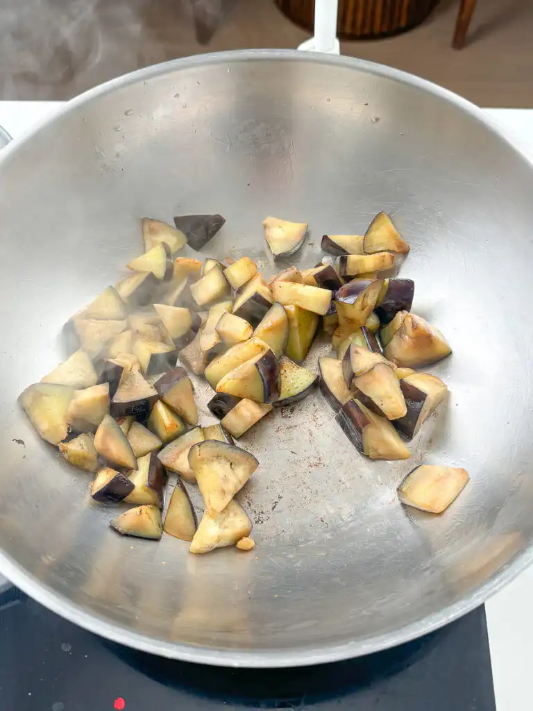 Eggplant searing in a hot pan with golden brown crust