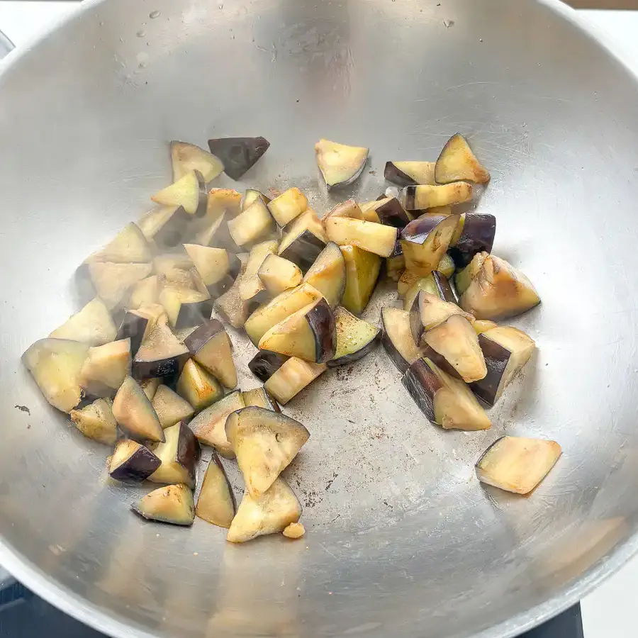Eggplant searing in a hot pan with golden brown crust