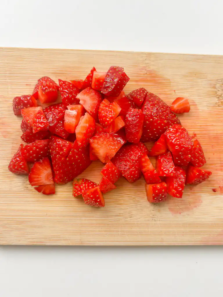 strawberries being cut into small cubes on cutting board to make matcha ice cream sandwich