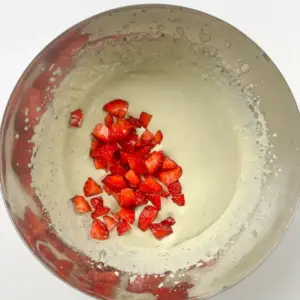Viral Strawberry Matcha Ice Cream Sandwich macerated strawberries draining through strainer over bowl - how to make strawberry matcha ice cream at home