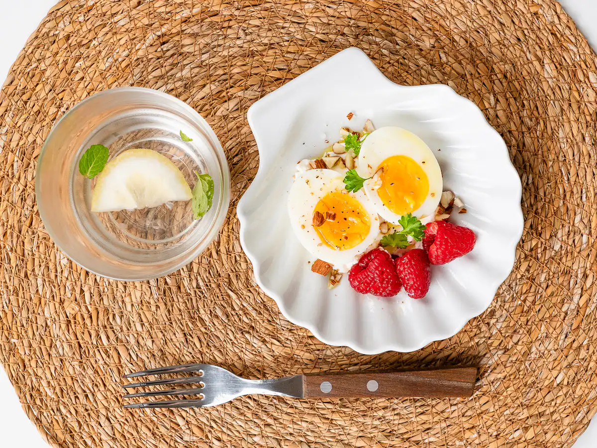 Natural Wegovy Healthy Egg Breakfast: GLP-1 Food natural wegovy glp-1 foods detail greek yogurt, eggs, olive oil, raspberries and rough almonds on plate close up