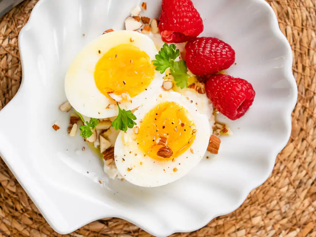 Natural Wegovy Healthy Egg Breakfast: GLP-1 Food oft boiled egg halved on ricotta with olive oil drizzle and black pepper closeup