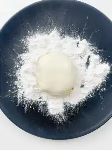 rolling rice paper mochi in rice flour to coat evenly