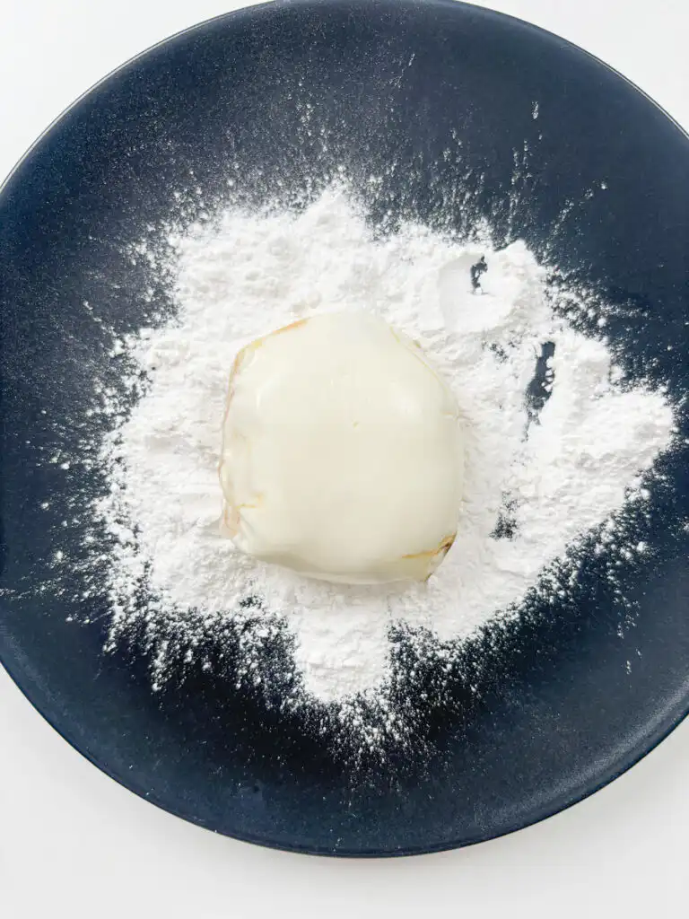 rolling rice paper mochi in rice flour to coat evenly