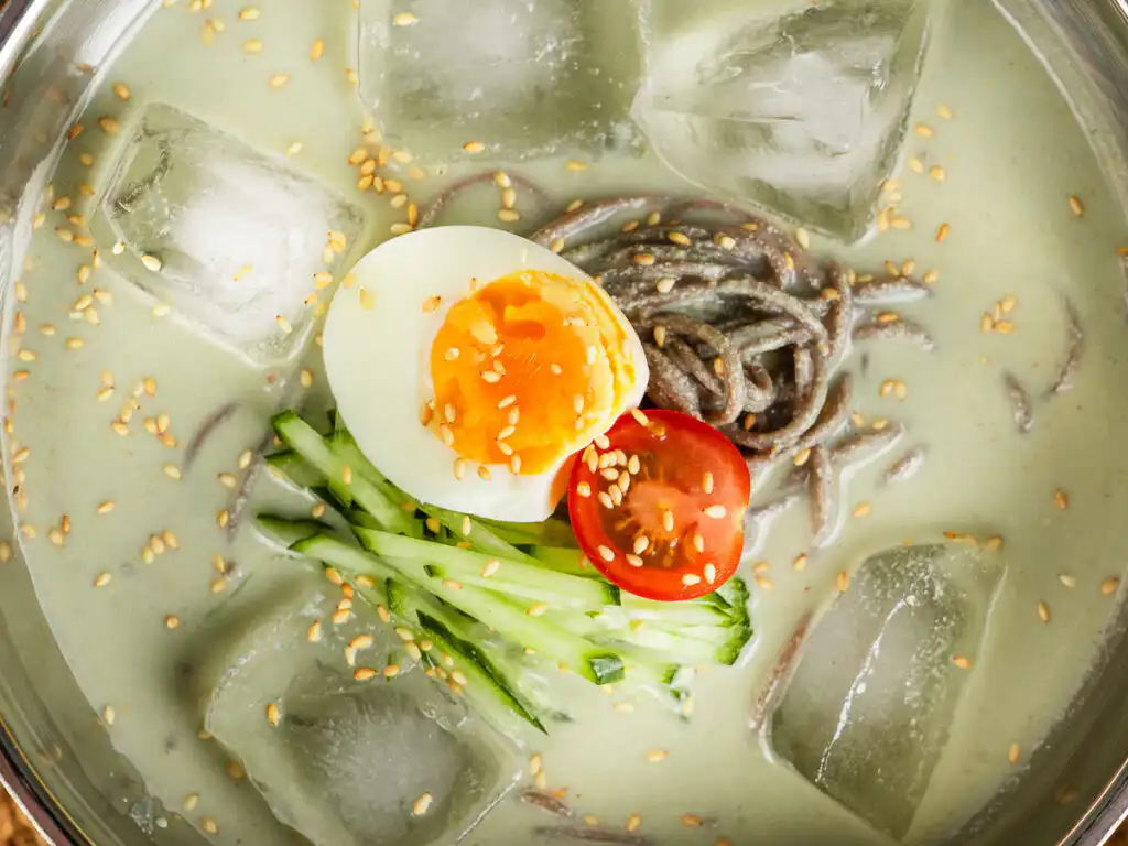 Matcha kongguksu close-up of the julienned cucumber topping on green soy broth