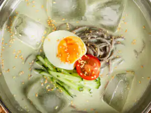 Matcha kongguksu close-up of the julienned cucumber topping on green soy broth