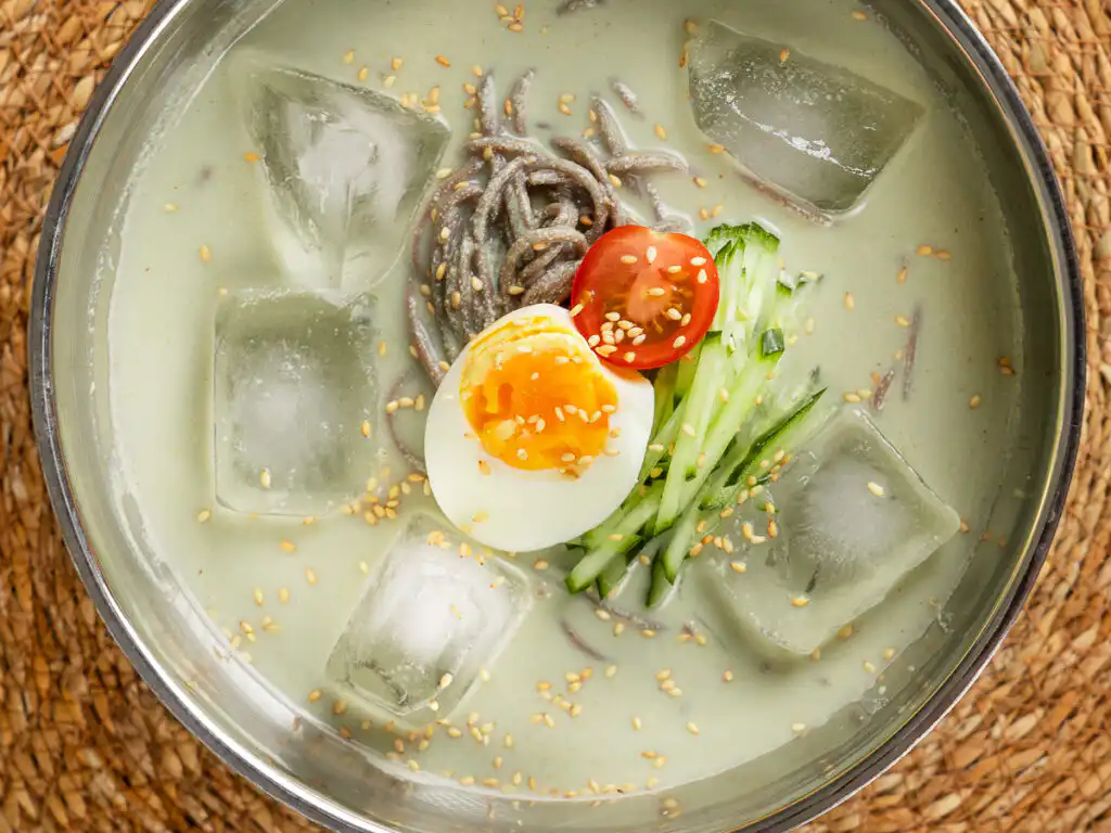 A stainless steel bowl of matcha kongguksu on a table