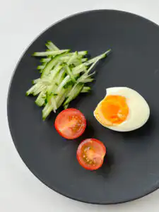 Julienned cucumber and halved boiled egg prepared as toppings for matcha kongguksu