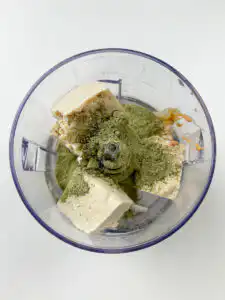 Tofu, matcha powder, and peanut butter being added to a blender for matcha kongguksu broth