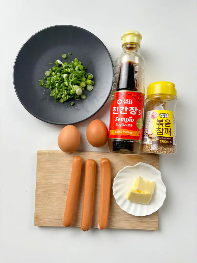 Sausage and Rice Recipe: 5-Min Korean Sausage Butter Rice Flat lay of sausage egg rice ingredients: pork sausages, two eggs, butter, Jin Ganjang, mirin, green onion, sesame