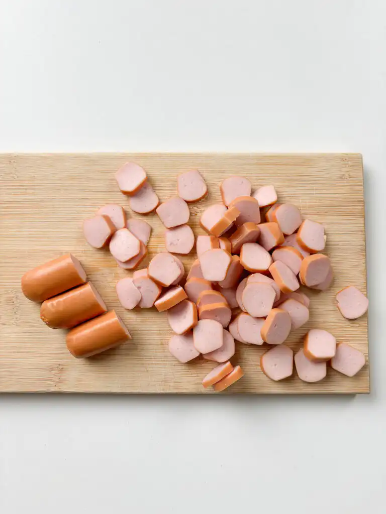 Slicing pork sausage into 0.5cm rounds for sausage and rice recipes Korean style, wooden board