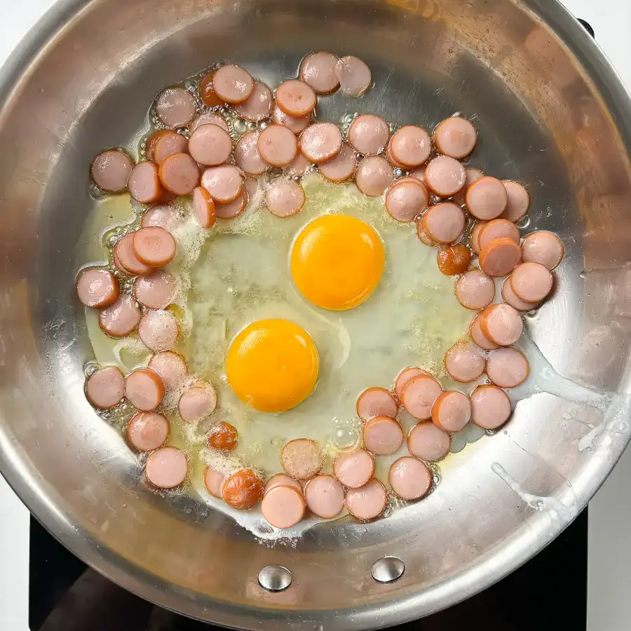 Sausage and Rice Recipe: 5-Min Korean Sausage Butter Rice Two eggs cracked directly into pan alongside golden sausage for sausage and rice recipes Korean bowl