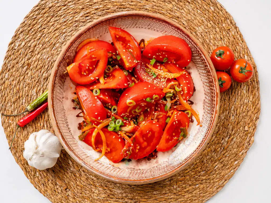Tomato Kimchi Recipe: No Fermentation, Ready in 10 Minutes tomato kimchi recipe in a white ceramic bowl with sesame seeds