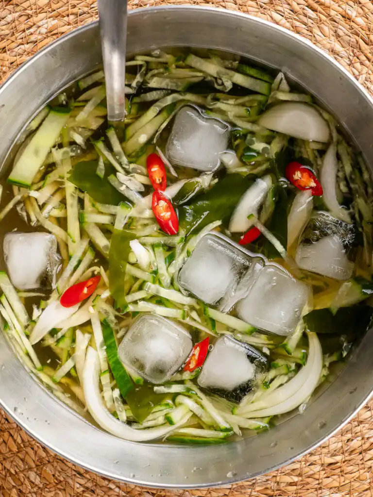 Korean Cucumber Soup (Oi Naengguk) - Best Cold Summer Soup Close-up of cold cucumber soup broth with julienned cucumber and rehydrated seaweed